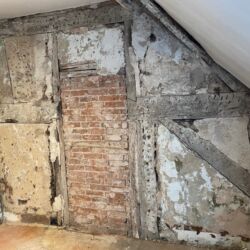 The partition wall in between the bedrooms was a combination of timber frame construction with a possible bricked up doorway. The plasterwork was loose or missing around the edges of the timbers, the plaster was missing over the brickwork.