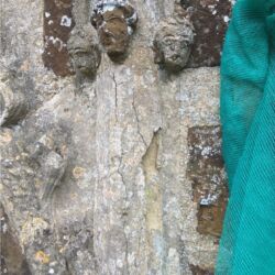 The central head is limestone, the other two are cement replacements, decaying stonework beneath.